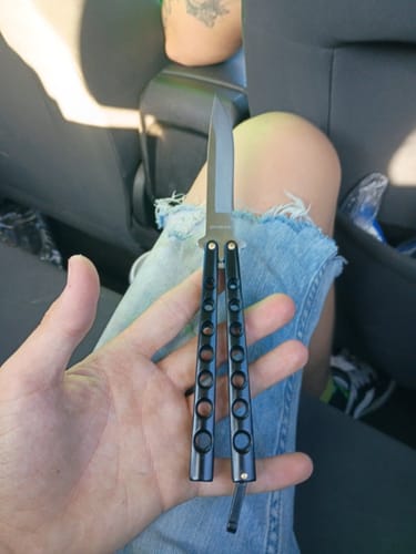 Customer holding the open Black Beast Butterfly Knife in their palm, showcasing its sharp blade.