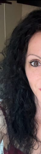Gros plan sur les cheveux foncés et brillants d'une cliente après avoir utilisé le soin sans rinçage au collagène.