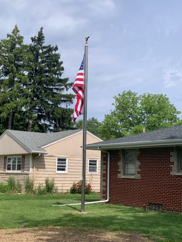 Customer's image of an American flag flying on a flagpole in a backyard.