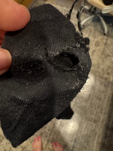Reviewer showing a large hole in a black Christian Performance Sock.