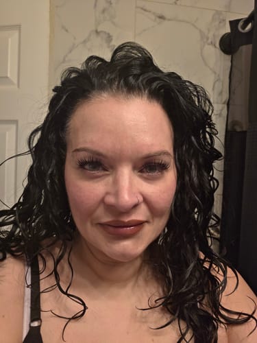 Customer showing a full, natural look with LuxeBold lashes in a bathroom selfie.