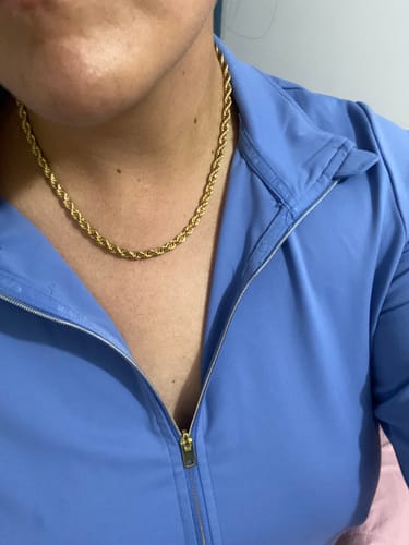 Reseñadora luciendo el Collar Elara dorado con una prenda azul con cremallera.