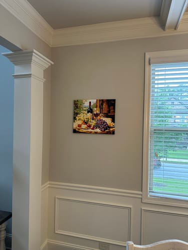 Customer's completed Vintage Vignette painting of a still life with wine and grapes hanging on a wall.