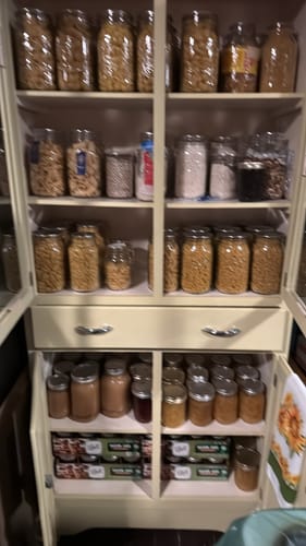Reviewer's organized pantry cabinet filled with food like pasta and beans stored in sealed mason jars.