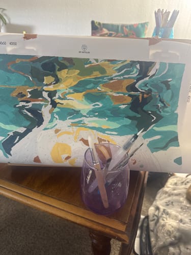 A customer's review image of their in-progress 'Under' Paint by Number canvas, with brushes ready in a glass.