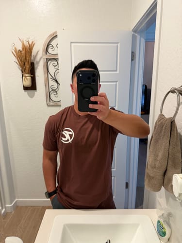 Reviewer showing the great fit of the brown YAMABUKI t-shirt from the front in a mirror selfie.
