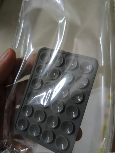 Customer holding the grey StickyPod in its clear packaging, showing the suction cups.