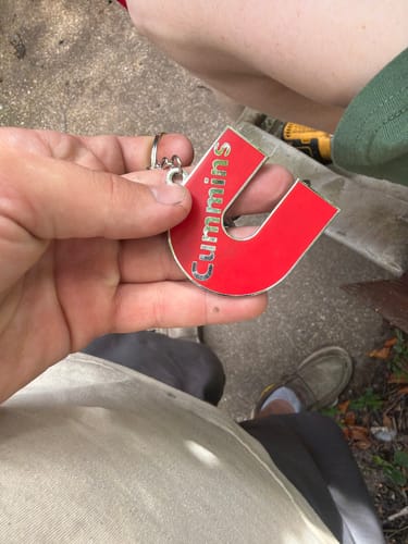 Reviewer holding the red, U-shaped Cummins keychain in their hand.