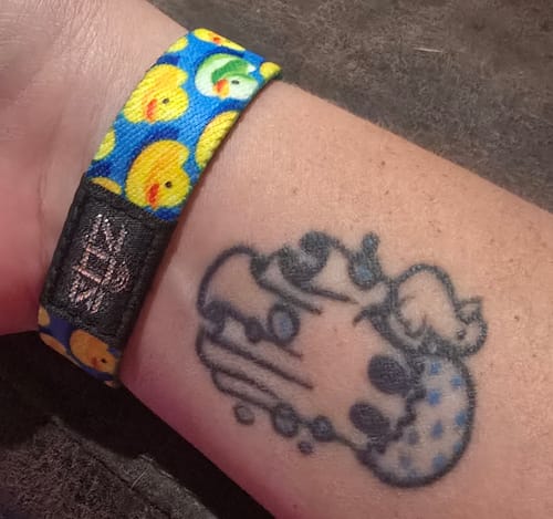 Customer wearing the Be the One Bracelet, showing the colorful yellow duck pattern on their wrist.