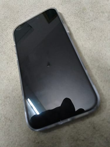 Reviewer's phone with the UltraShield Tempered Glass applied, showing a smooth, reflective screen.