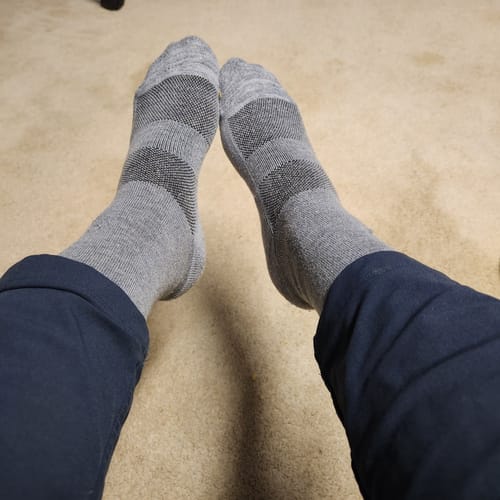 Reviewer's feet propped up while wearing the soft grey Crew Socks with darker bands.