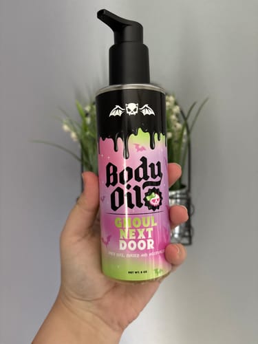 Customer's hand holding the colorful bottle of Ghoul Next Door Body Oil.