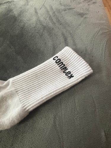 Reviewer's close-up of a white Everyday Sock, showing the ribbed cuff and black 'Complex' logo.