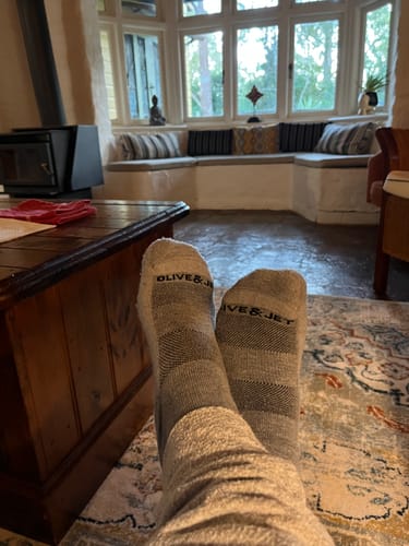 Customer relaxing in cosy grey Quarter Socks with their feet propped up in a living room.