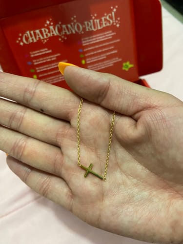 Cliente sosteniendo el Collar Goddes dorado con una cruz en la palma de su mano.