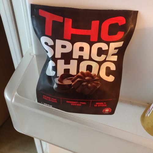 Rezensent zeigt die schwarze Verpackung von THC SpaceChoc, die in einem Kühlschrankfach aufbewahrt wird.