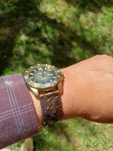 Cliente luciendo su reloj con la correa Cobra Hex de piel de pitón marrón en la muñeca al aire libre.