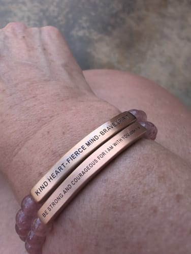 Customer wearing the rose gold 'BE STRONG AND COURAGEOUS' bracelet stacked with another on their wrist.