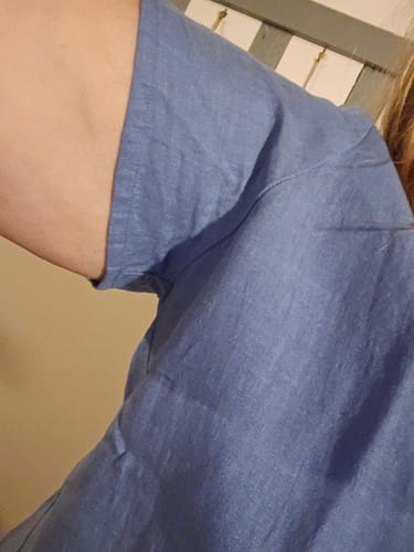 Gros plan d'une cliente sur la manche serrée de sa blouse Emeline en lin bleu.