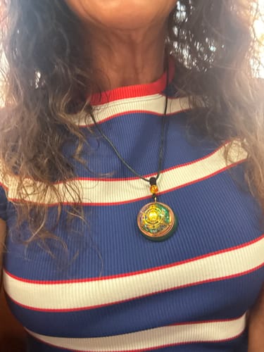 Customer wearing the round Magnetic Energy Talisman necklace against a striped shirt.