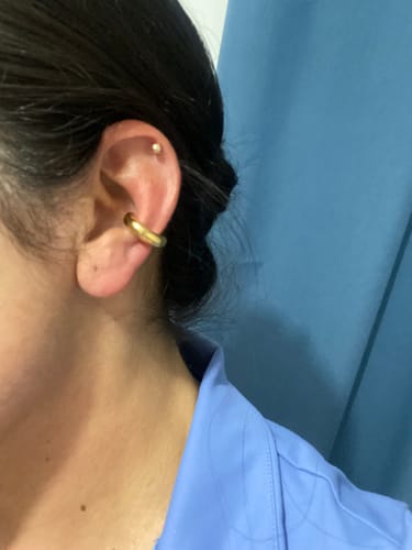 Cliente mostrando su accesorio sorpresa, un ear cuff dorado y grueso, en la oreja.