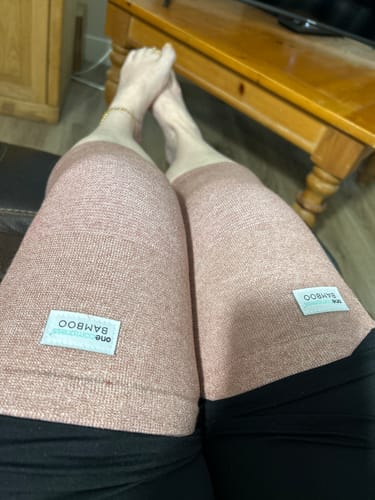 Reviewer relaxing on a couch, wearing pink Premium Bamboo Knee Sleeves on both legs.