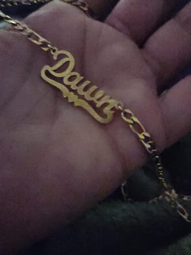 Close-up of a reviewer's hand holding the Diamond Cut Heart Name Necklace with the name 'Dawn'.