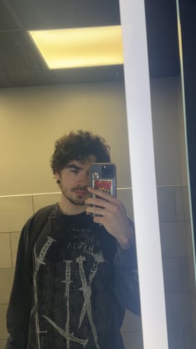 Reviewer in a mirror selfie wearing the graphic Iron Edge Longsleeves, showing its relaxed fit.