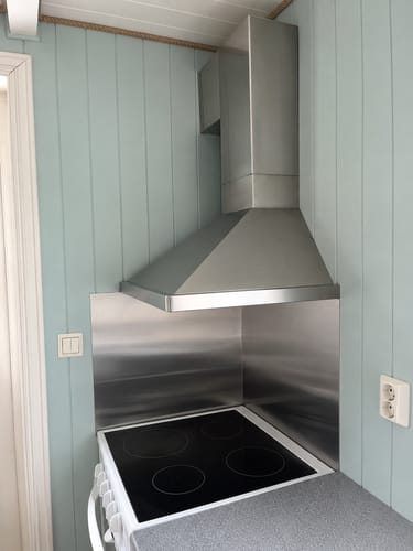 Anmelderens kjøkken med en stålplate som backsplash før montering av de selvklebende flisene.
