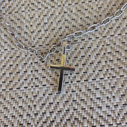Close-up of a customer's small Moissanite Cross pendant on a silver paperclip chain.