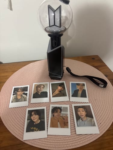 Reviewer's BTS Official Light Stick Ver.4 displayed with the complete set of seven member photocards on a table.