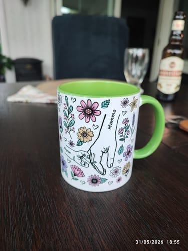 Kundens Kärleksmugg med grönt handtag och insida, med ett blommigt tryck och namnet 'Mamma'.