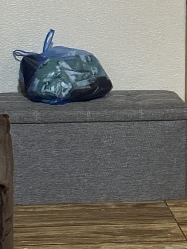 Un cliente muestra su Banco Baúl Organizador de tela gris en su casa.