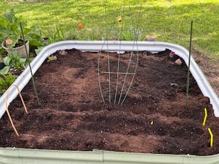 Customer's 17” Tall Modular garden bed filled with soil and a center trellis, ready for planting on a green lawn.
