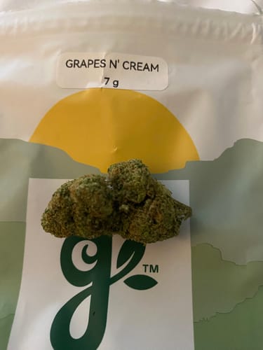 Customer's close-up of a Grapes N' Cream flower bud in front of its packaging.