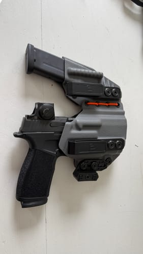 Customer's gray AXIS ELITE holster holding a black handgun and a magazine, connected by orange cord.