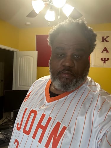 A reviewer wearing the custom white and orange pinstripe pullover baseball jersey indoors.