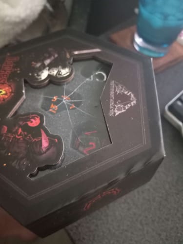 Customer's Darkest Dungeon Dice Set box, showing the cracked plastic window and a warped edge.