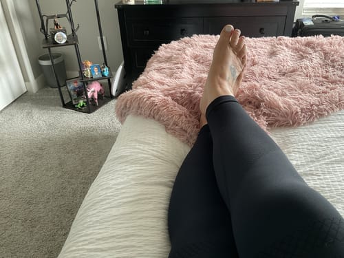 Reviewer relaxing on a bed, showing the fit of the black 3D Anti-Cellulite Leggings on their legs.