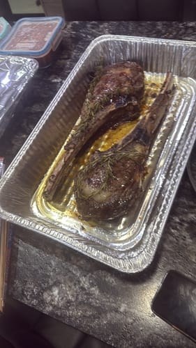 Dos filetes Rib Eye Choice de un cliente, asados con hierbas en una bandeja de aluminio.