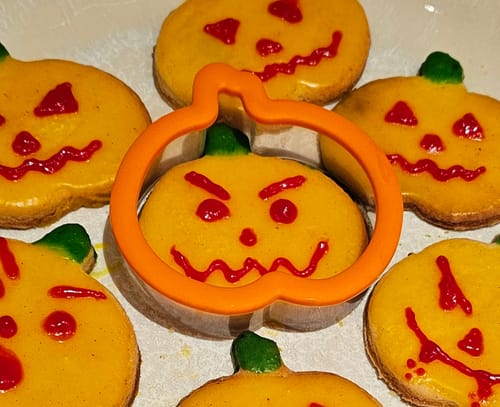 Kundin zeigt ihre fertigen Kürbis-Kekse und die passende Halloween-Ausstechform.