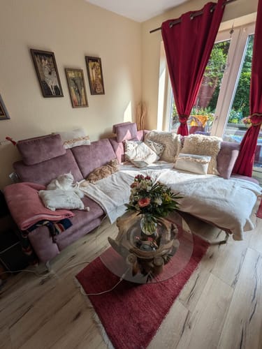 Ein Kunde zeigt den Wurzeltisch ZEN aus Wurzelholz mit Glasplatte in einem hellen Wohnzimmer.