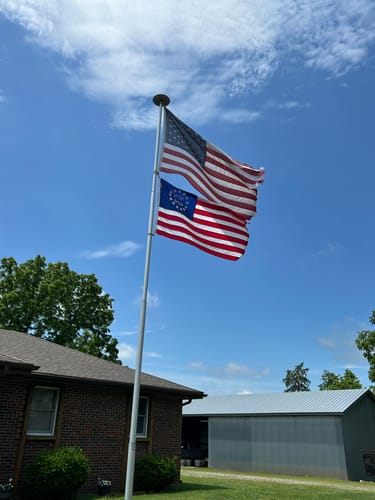 Customer's image showing two American flags flying on a flagpole against a blue sky.