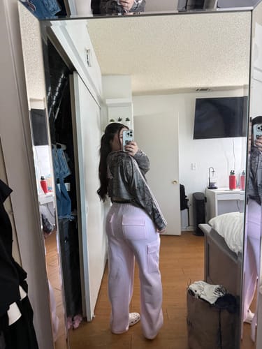 Reviewer showing the oversized fit of the Camo Longsleeve Jersey from the side, styled with pink pants.