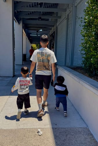Reviewer from behind wearing the white Fuji Mart T-shirt while walking outdoors with two children.