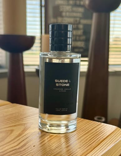 Customer's Suede & Stone Eau de Parfum bottle with a black label on a wooden table.