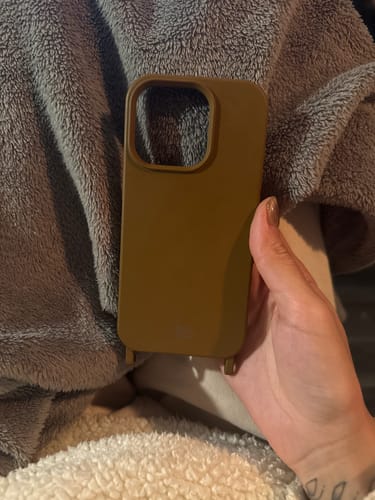 Cliente segurando a Case marrom Mocha Mousse, com detalhe dos encaixes para alça.