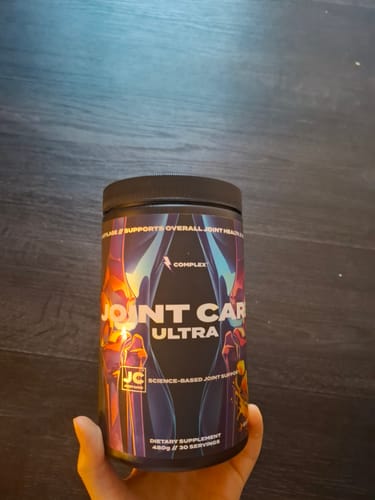 A customer holding the black tub of Joint Care Ultra, showing its vibrant, colorful label.