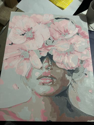 Customer's paint-by-numbers canvas showing a woman's face with large pink flowers covering her eyes.