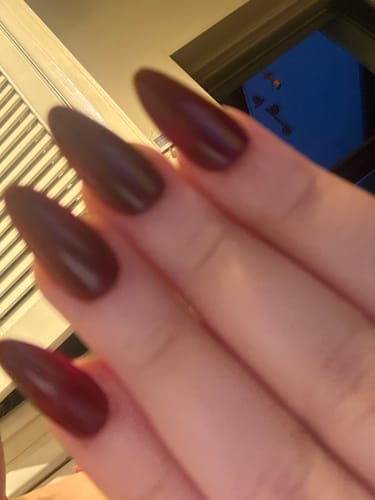 Close-up of a customer's hand showing the long, almond-shaped Red Wine press-on nails.
